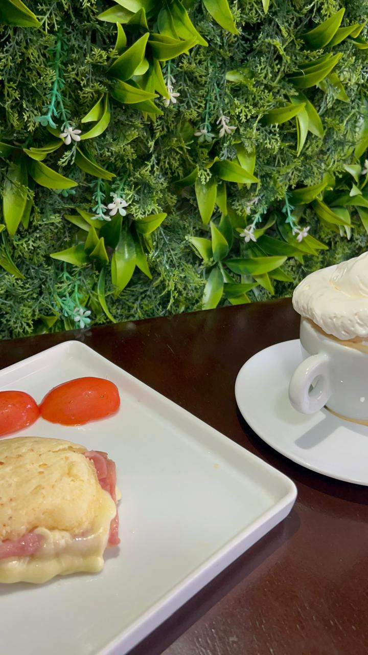 Misto na chapa e cappuccino diante da parede verde do Esquina Du Café